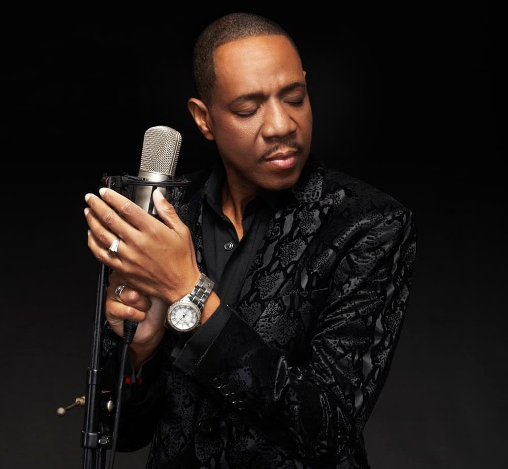 R&B singer Freddie Jackson in a studio portrait holding a vintage microphone